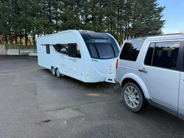 Touring caravan beside a tow vehicle on a paved area